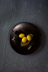 green olives on plate on black background