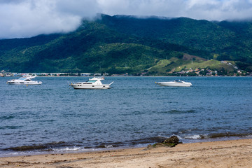 Vário barcos na praia com uma ilha ao fundo