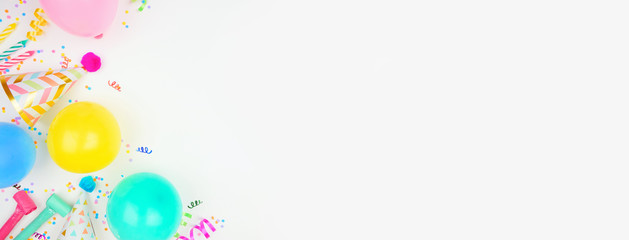 Birthday party banner with corner border on a white background. Overhead view with balloons, party hats, streamers and confetti. Copy space.