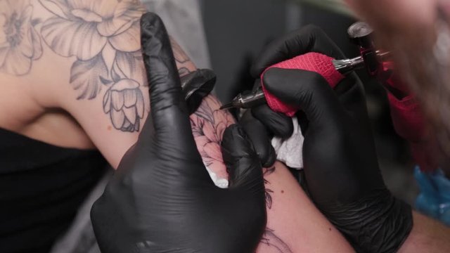Tattoo artist makes a tattoo on a young girl's arm.