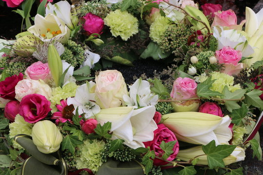 Edler Blumenkranz nach einer Beisetzung am Friedhof, Trauerkranz mit Rosen und weißen Lilien, Floristik