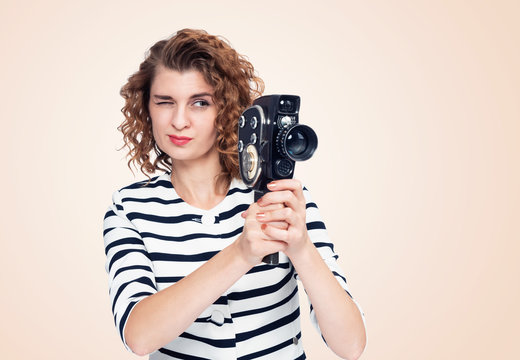 Young girl holding an old movie camera 8mm in her hands, on yellow light background