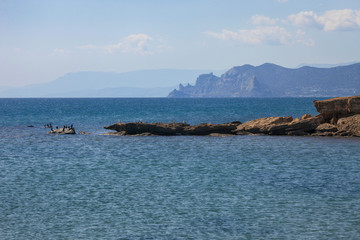 Nice view of the Black Sea coast in Crimea. Birds on rocks in the sea and a mountain in the distance