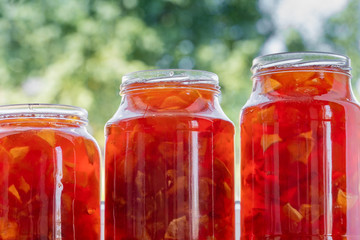 Apple jam in a different sizes glass jars on the nature background. Concept of eco product and harvest of summers fruits. Close-up.