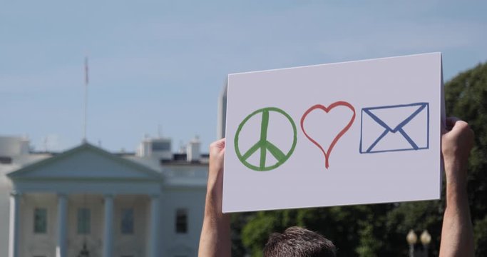 WASHINGTON, DC - Circa June, 2020 - A man waves a handmade PEACE LOVE MAIL protest sign outside the White House. The US Postal Service was the focus of attention during the 2020 presidential election.