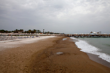 Beach with sun loungers umbrellas during rain on a rainy day