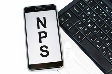 phone with the text NPS NET PROMOTER SCORE on the laptop keyboard. Business concepts