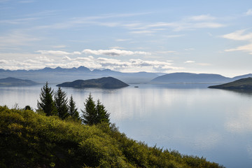 Fototapeta na wymiar Islands spiegelglatte Seen mit Bergen im Hintergrund und blauem Himmel mit Wolken