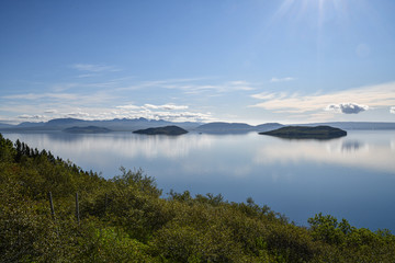 Islands spiegelglatte Seen mit Bergen im Hintergrund und blauem Himmel mit Wolken