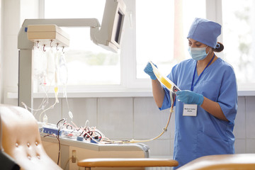 Nurse in uniform preparing dropper for donor she is in blood donation laboratory