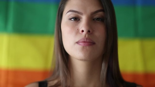 Portrait young lesbian woman smiling to camera with LGBT pride rainbow flag
