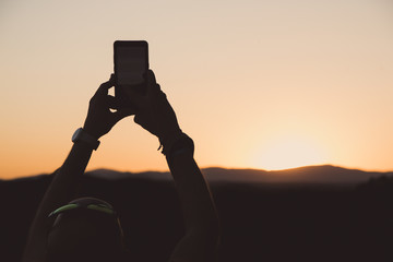 A man photographing sunset over the Madrid in Spain by a smartphone