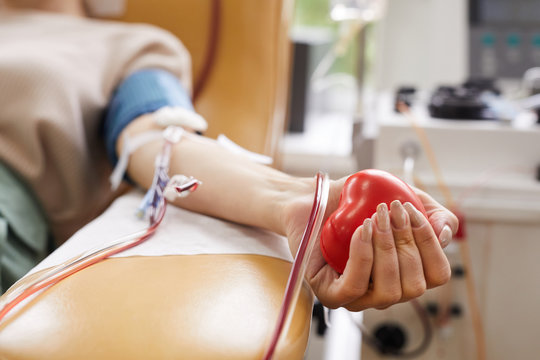 Close-up of patient with tubes in her arm squeezing the ball in her hand while donating the blood
