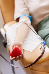 Close-up of donor holding ball in her hand and donating blood at the lab - obrazy, fototapety, plakaty