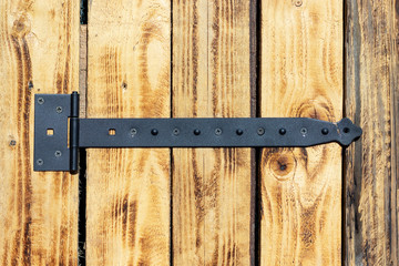 Big black hinge on door made of wooden boards.