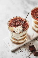 Portion dessert tiramisu in a glass on a marble background