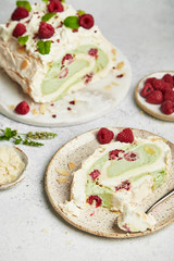 Merengue roll with pistachio cream and raspberry on a bright background