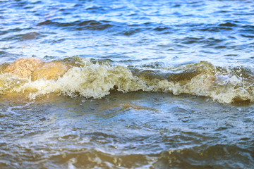 A small sea wave beating against a garnit boulder