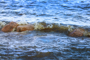 A small sea wave beating against a garnit boulder