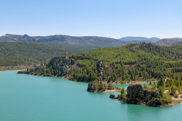 View from above of the beautiful Taibilla reservoir in Kastillen. Impressive rocks stand in the water and on the shore. In the background a beautiful mountain landscape.