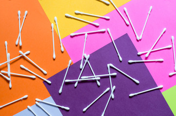 Cosmetic cotton swabs on a multicolored background top view. Skin care products