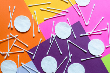 Cosmetic cotton swabs and cotton pads on a multicolored background top view. Skin care products.