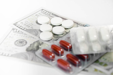 red and white pills lie on money and white background