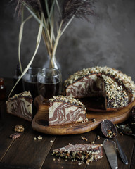 Zebra cake pieces on a wooden cutting board. Still life in dark shades. Homemade sweets.