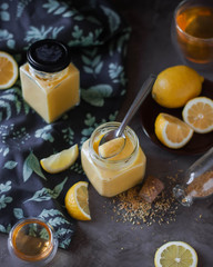 Lemon curd in a glass jar on the table. View from above. Slices of citrus.
