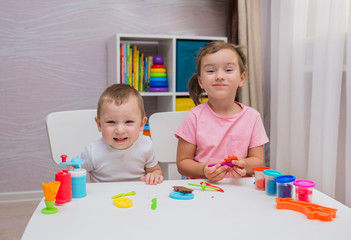 Fototapeta premium happy children play with plasticine at the table in the room