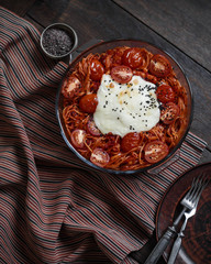 Pasta with tomato paste and cheese in a glass bowl. Baked pasta with burrata. Hot food.