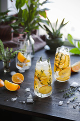 Classic lemonade with thyme and ice in a glass on a dark table. Cold refreshing drink.