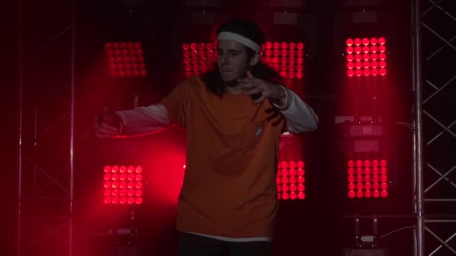 Portrait of young man professional hip-hop dancer performing modern dance in studio concentrated on moves. Dynamic multicolored lighting effects .Close up. Slow motion.