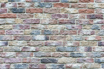 View of old shabby wall made from multicolored bricks. Abstract textured background. Copy space for your text and decorations.