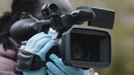 Young african man holding video camera with medical gloves. Reporting about covid19 spread. High quality photo