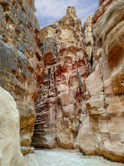 The Siq gorge in Jordan, leading to ancient Petra city. Reddish sandstone cliffs. Blue sky with clouds. Beautiful landscape theme.