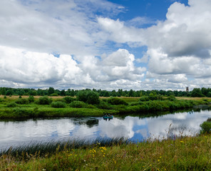 A quiet river, a sky and a boat with people.
