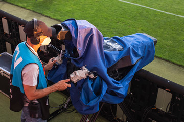 Cameraman with protective mask works during soccer match.