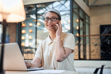 Grey-haired businesswoman in glasses having a phonecall