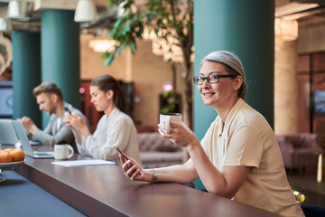 Adult smiling female in glasses holding mug with drink