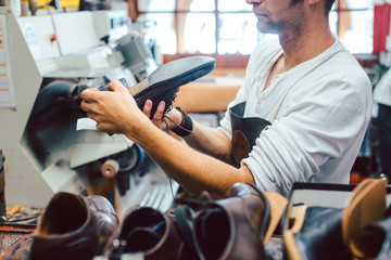 Shoemaker roughing the sole of a leather shoe