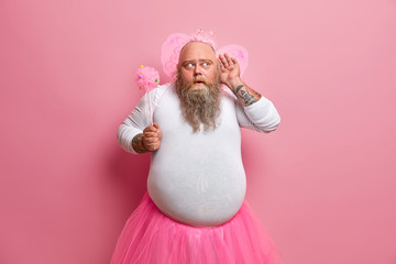 Funny fatso man in princess outfit, holds magic wand, wears pink wings, has big fat belly, keeps...