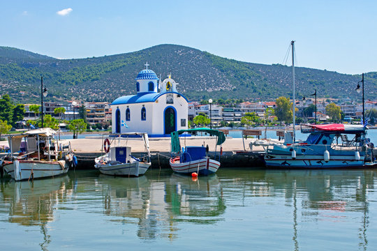  Fishing boats and  the chapel of Saint Nikolaos  in the port of Nea Artaki , Euboea / Greece . Sunny summer day 
