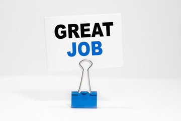 GREAT JOB inscription on a white business card on a white endless background in a blue clip.