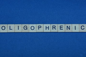 gray word oligophrenic in small square wooden letters with black font on a blue background