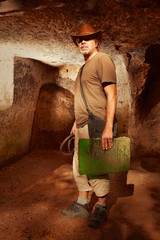 Adventurer in ancient cave on trace of mysterious emerald tablet finding famous artifact