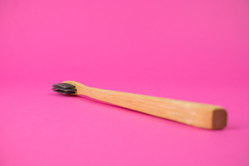 bamboo toothbrush on pink background, side view. Natural organic bathroom beauty product. Copy space