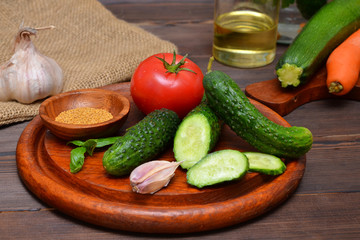 fresh vegetables ingredients for making salad with cucumbers and tomatoes and spices in the kitchen