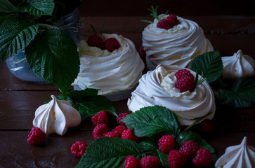 Mini Pavlova cake with raspberries on a dark background