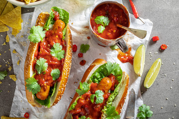 Unhealthy barbecue hot dogs with red sauce and coriander